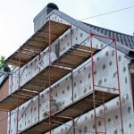 Building facade under renovation works with construction scaffolding frame.